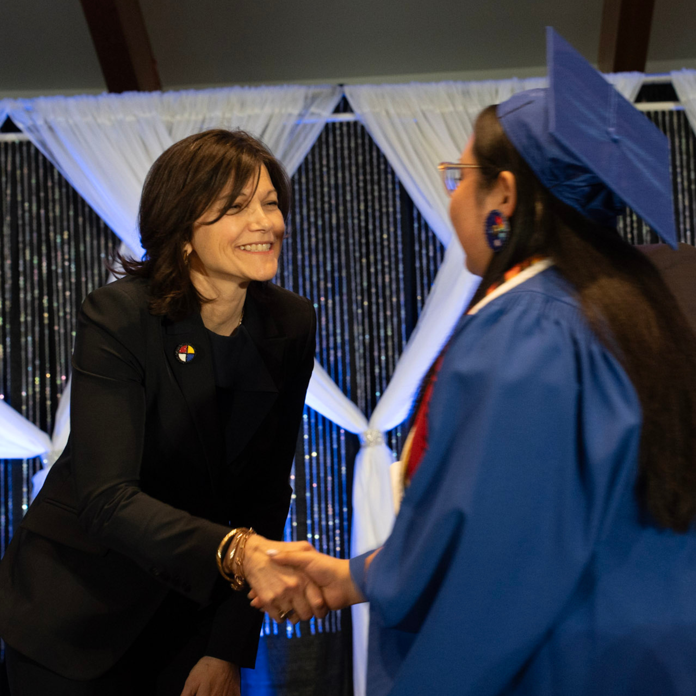 Chief Superintendent Lynnette Anderson shaking hands with a student wearing a graduation cap and gown